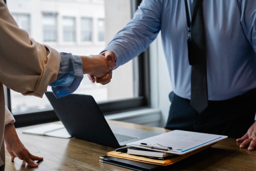 A loan applicant shaking hands with a lender in an office after completing the title pawn process. 