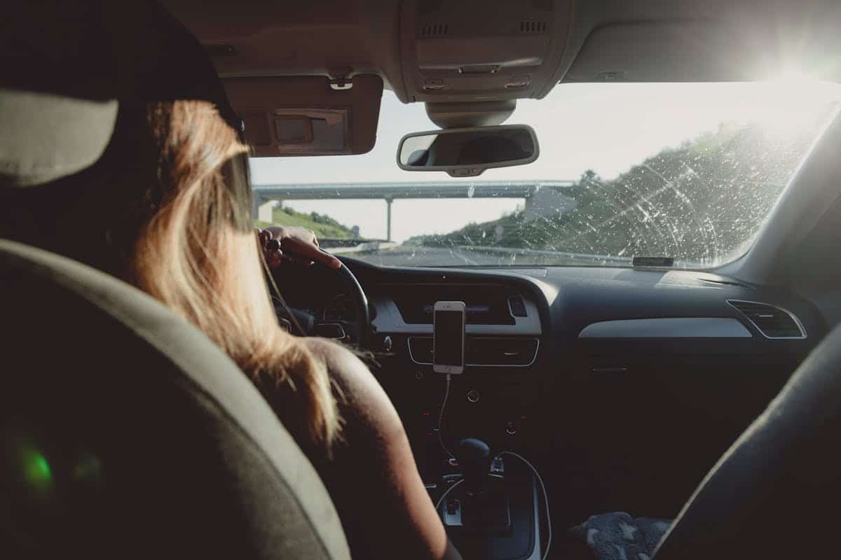 A woman confidently driving her vehicle on a sunny day, representing the empowerment and financial relief title loans can provide