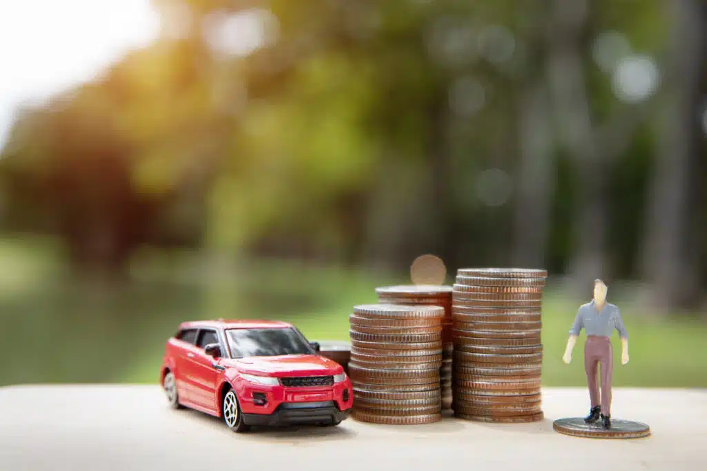 Red miniature car placed on several stacks of coins arranged in ascending order.